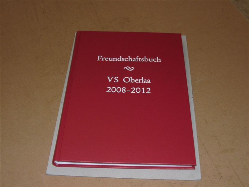 Rotes Klassenabschlussbuch einer Volksschule mit heller Prägung auf dem Deckel